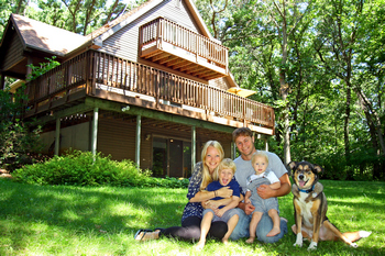A smiling family stands together in front of their home, showcasing a warm and joyful moment.