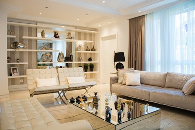 A bright living room showcasing white furniture paired with a glass coffee table.