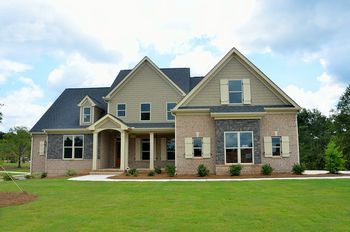 A spacious brick house set in a large grassy yard.