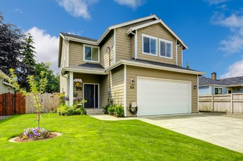 A picturesque home with a manicured yard and ample driveway space.