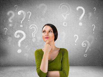 A woman is lost in thought, staring at question marks on a wall, symbolizing her curiosity and questions about USDA loans